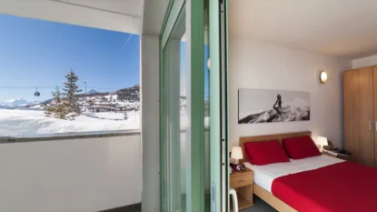 Camera da letto con vista sulle montagne innevate attraverso la finestra