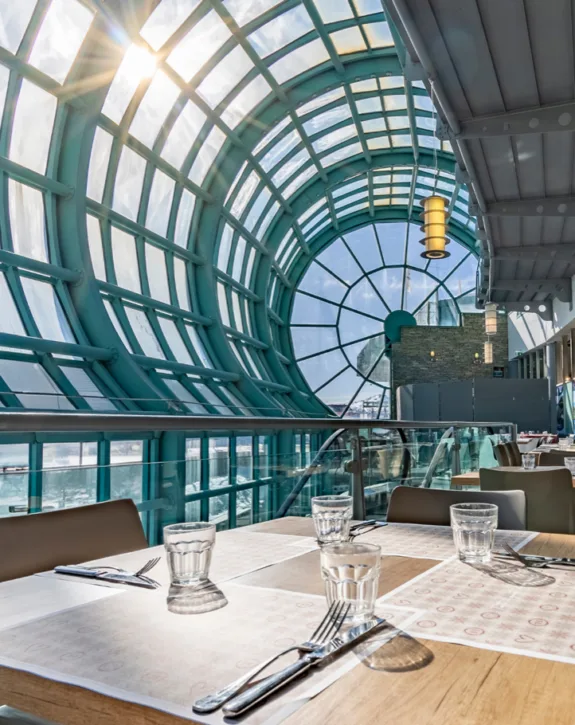 Ristorante panoramico con soffitto vetrato ad arco e tavoli apparecchiati