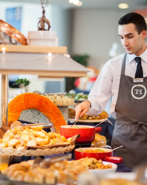 Cameriere serve piatti al buffet con pane e pietanze varie