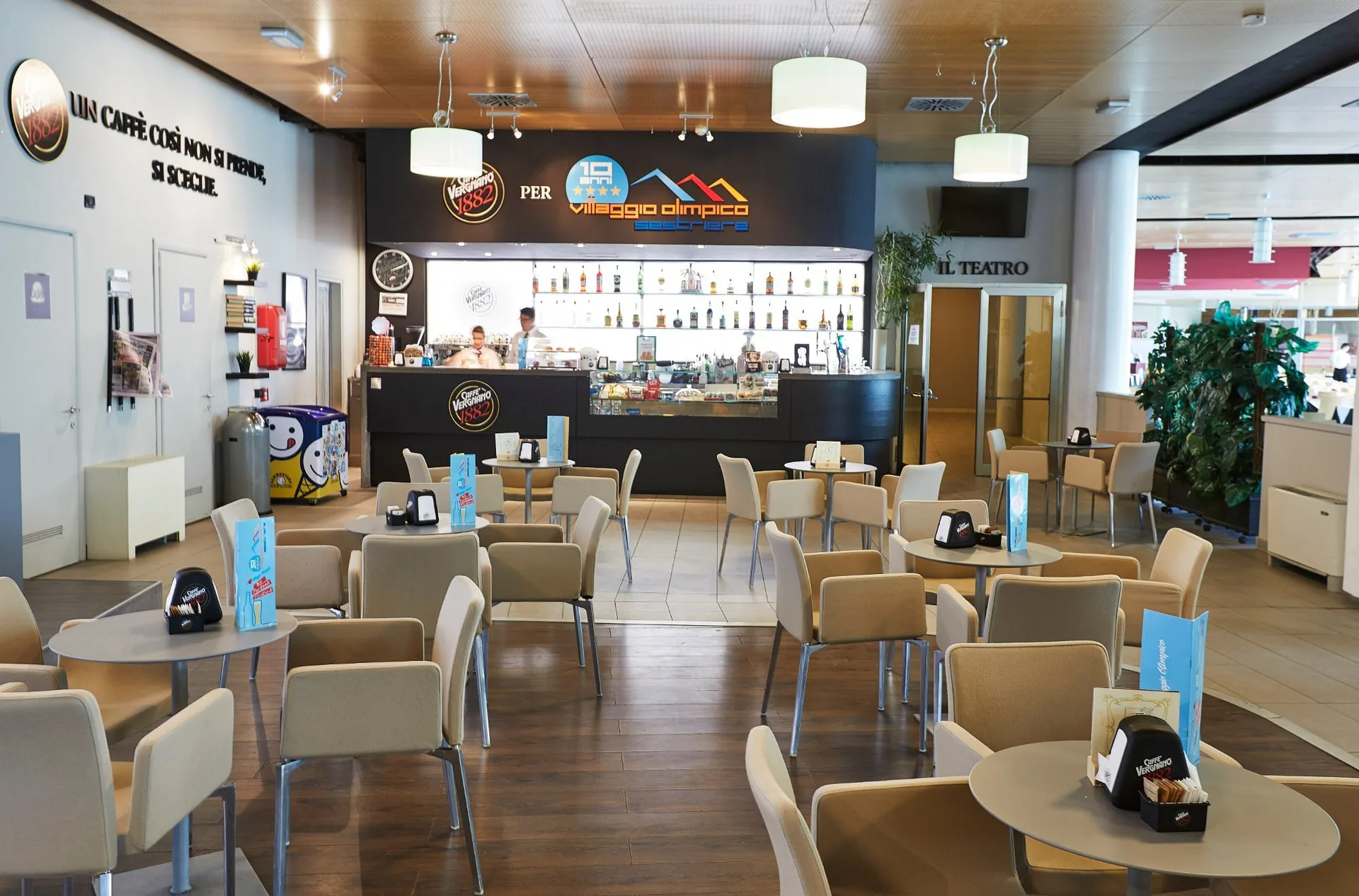 Area bar caffetteria con tavolini, sedie beige e bancone