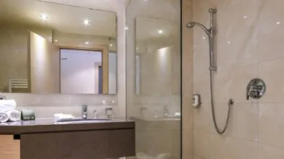 Bagno moderno con doccia, specchi e lavandino, arredato con asciugamani e prodotti da bagno, illuminazione soft.