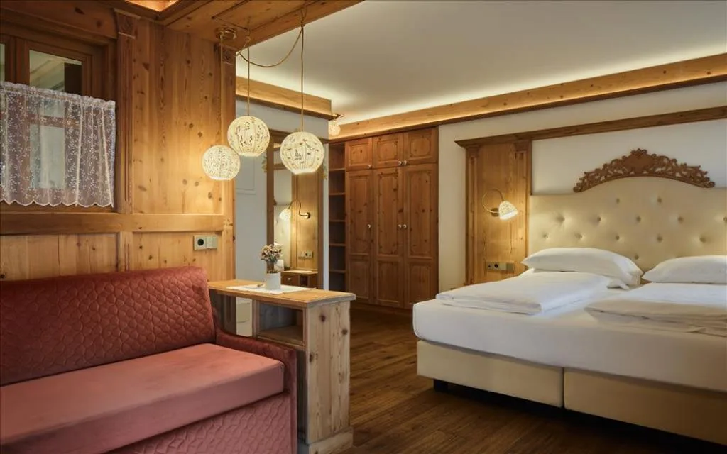 Camera elegante con testiera imbottita, boiserie in legno e divano rosa