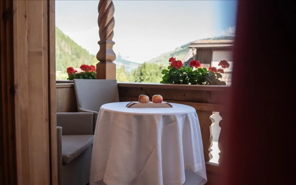 Balcone con tavolino, mele e gerani rossi con vista sulle montagne