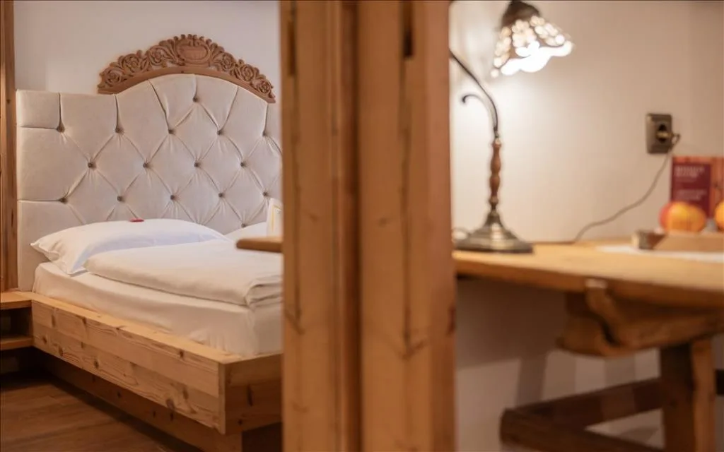 Dettaglio di letto con testiera imbottita e scrivania in legno