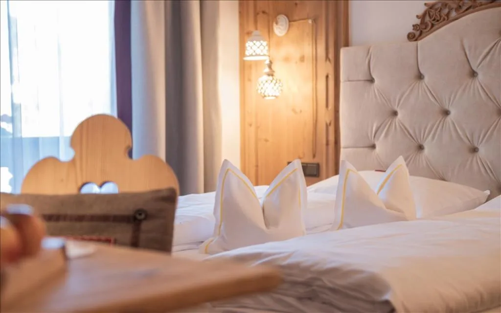 Letto matrimoniale con cuscini decorativi e applique in legno