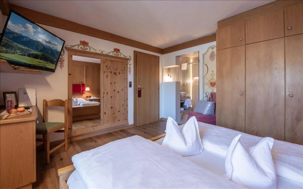 Camera con letto, TV, guardaroba in legno e decori floreali dipinti