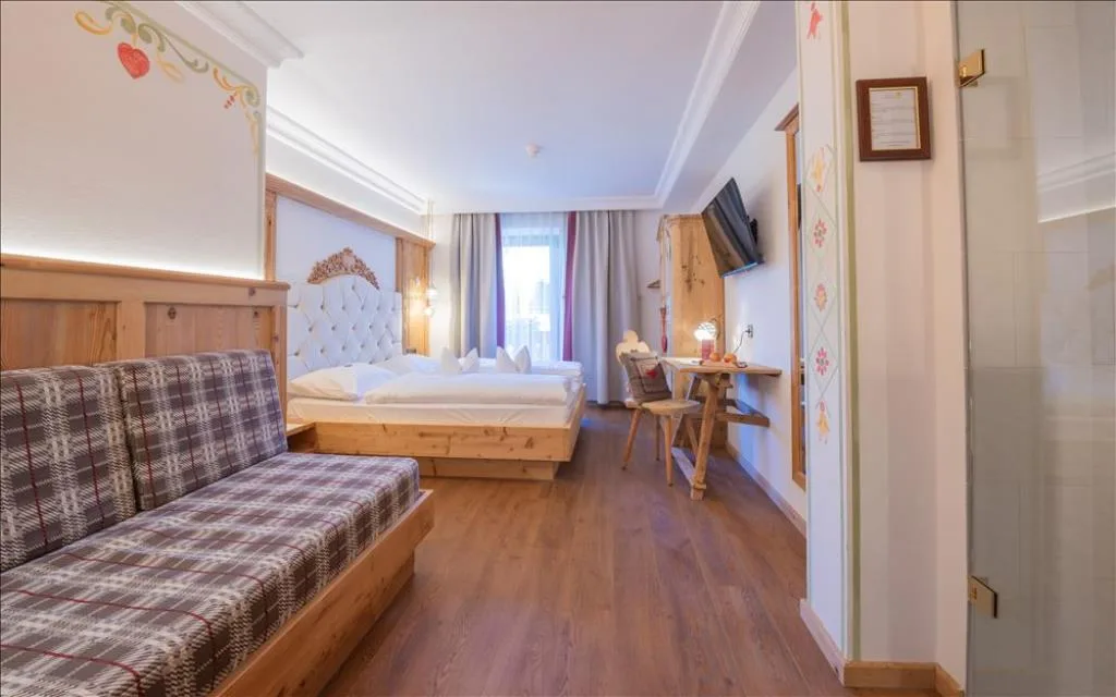 Camera luminosa con letto matrimoniale, divano e scrivania in legno