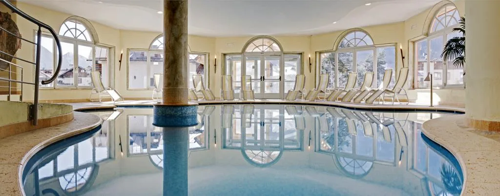 Piscina coperta con colonna centrale, lettini e ampie finestre ad arco