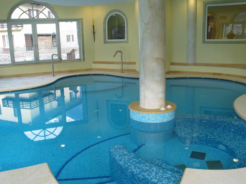 Piscina interna con mosaico azzurro, colonna centrale e finestre ad arco