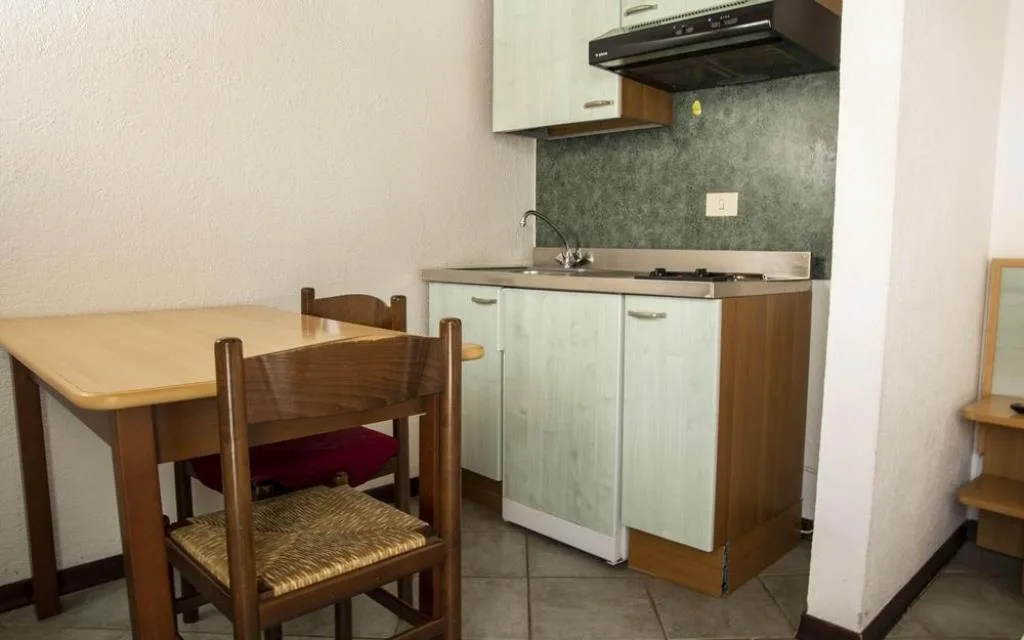 Angolo cottura con piano cottura, cappa, lavello e tavolo in legno con sedie