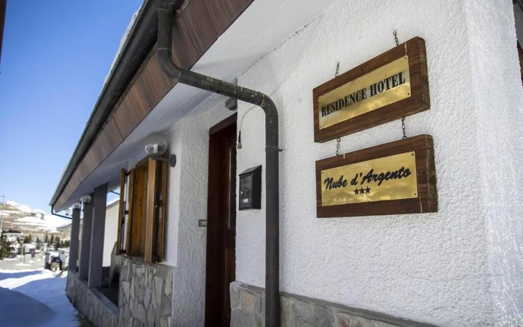 Insegne in ottone Residence Hotel Nube d'Argento tre stelle sulla parete esterna bianca