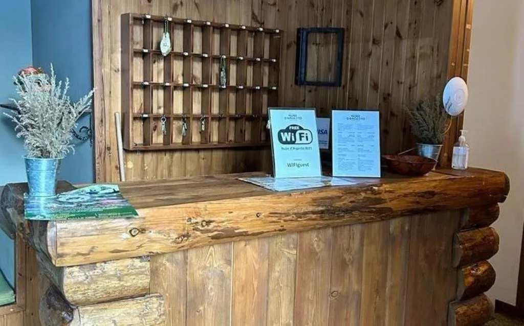 Reception in legno rustico con bacheca portachiavi e cartello Wi-Fi gratuito