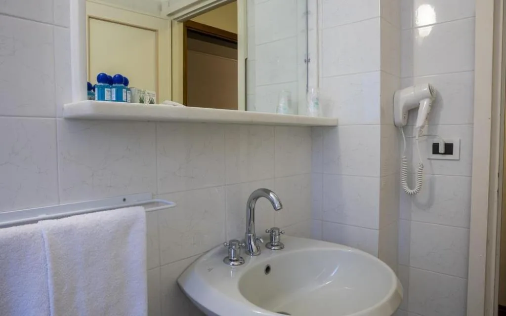 Angolo bagno con lavabo bianco, specchio, asciugamani e asciugacapelli