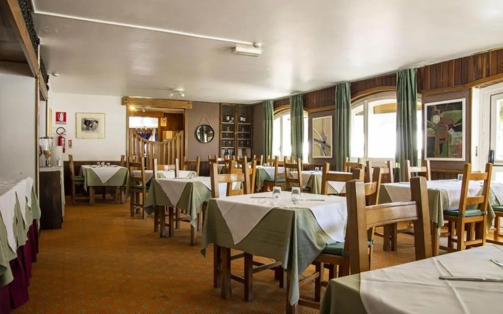 Sala ristorante con tavoli apparecchiati, tovaglie verdi e pareti in legno