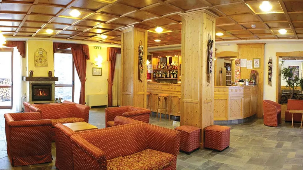 Hall dell'hotel con poltrone, camino e bar in legno chiaro