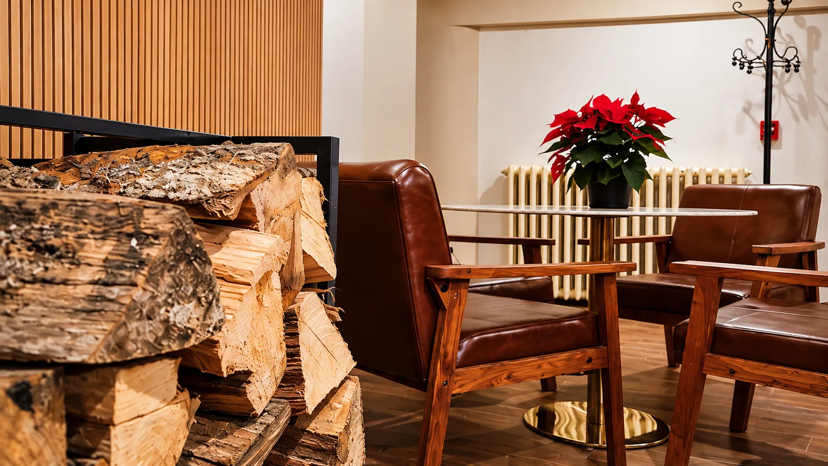 Dettaglio della lounge con legna da ardere, poltrone in pelle e stella di Natale