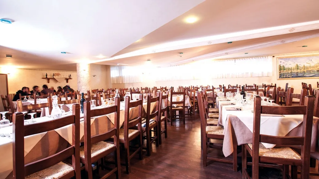 Sala ristorante dell'hotel con tavoli apparecchiati e sedie in legno