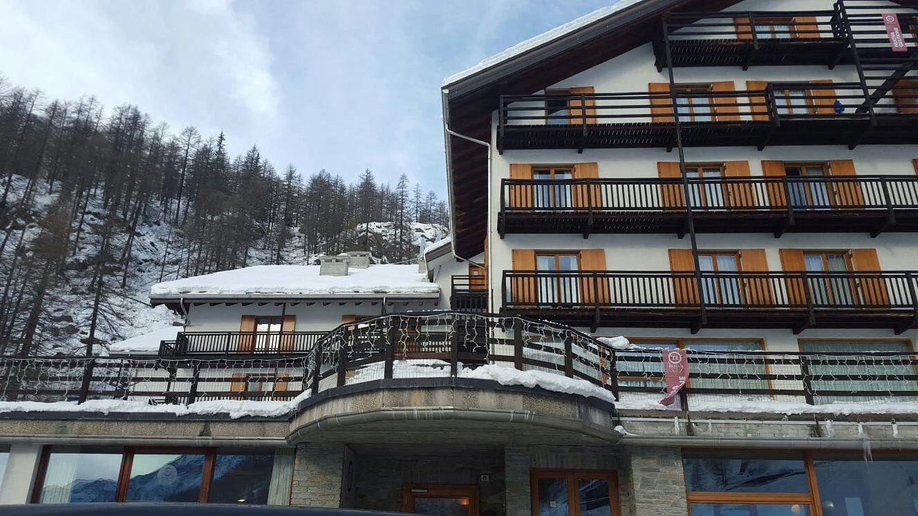Dettaglio della facciata dell'hotel con balconi in legno e terrazza curva coperta di neve