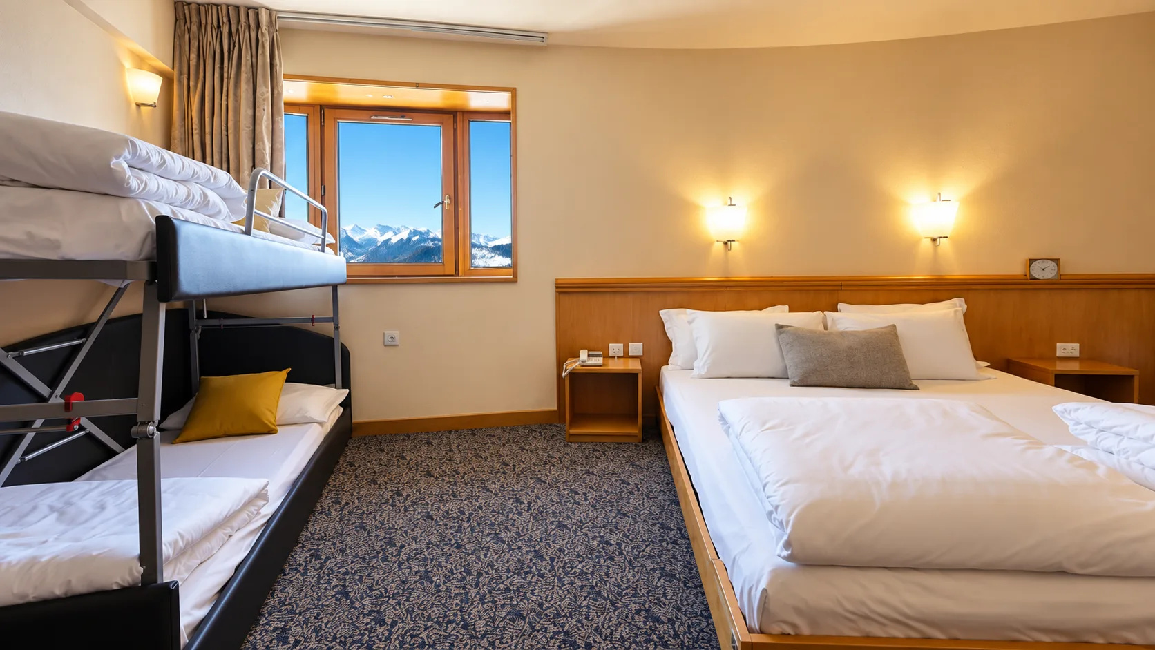 Camera familiare con letto matrimoniale e letto a castello, finestra con vista sulle montagne innevate