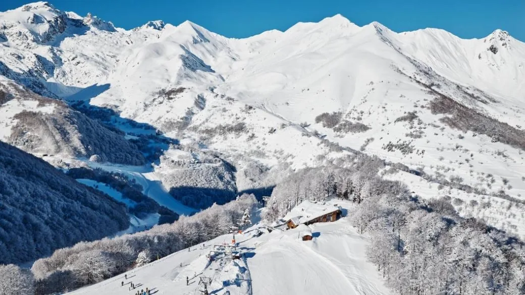 Vista panoramica delle montagne innevate con chalet e impianti di risalita