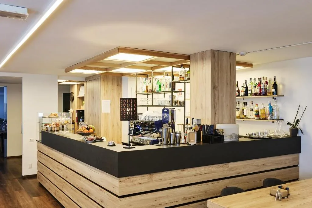 Bancone bar in legno dell'hotel con bottiglie, caffettiera e dolci esposti