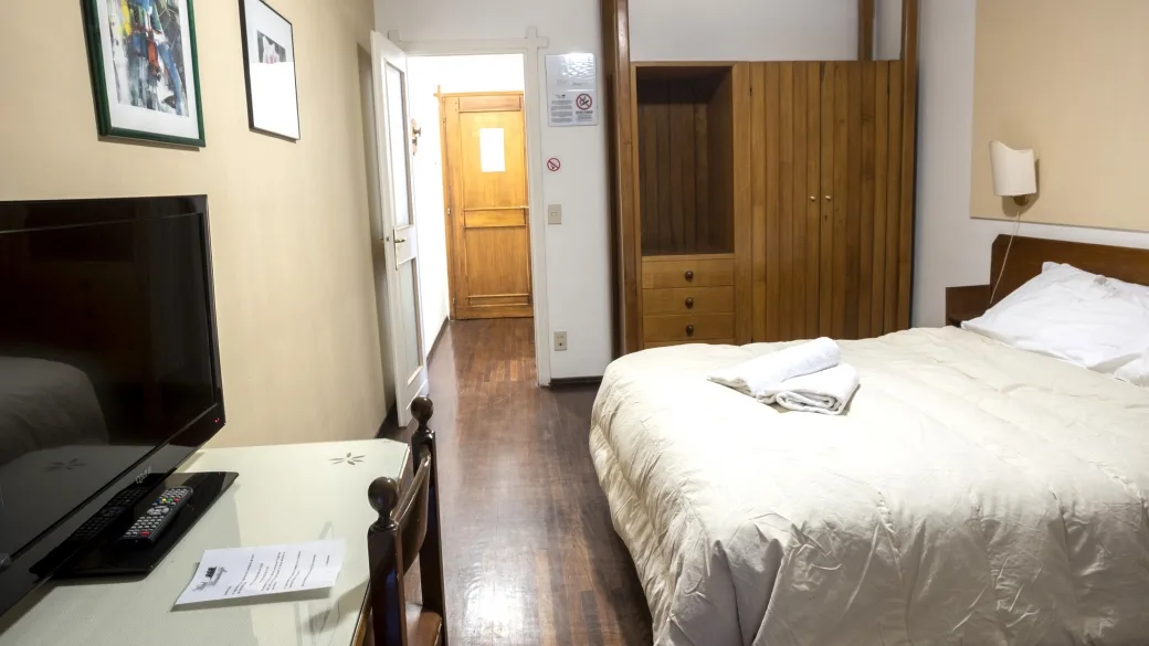 Camera da letto con letto matrimoniale, TV, armadio in legno e scrivania