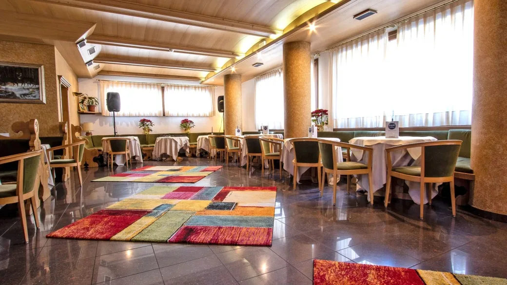 Sala da pranzo dell'hotel con tavoli apparecchiati e tappeti colorati