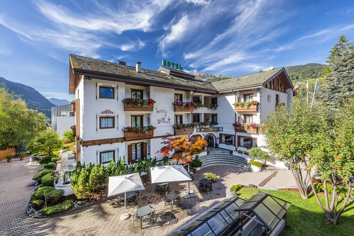Facciata dell'Hotel Sant'Anton in estate con giardino, cortile e ombrelloni