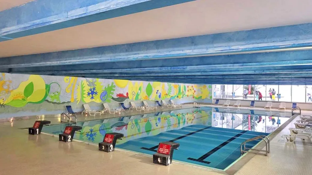 Piscina coperta con decorazioni colorate alle pareti e blocchi di partenza numerati