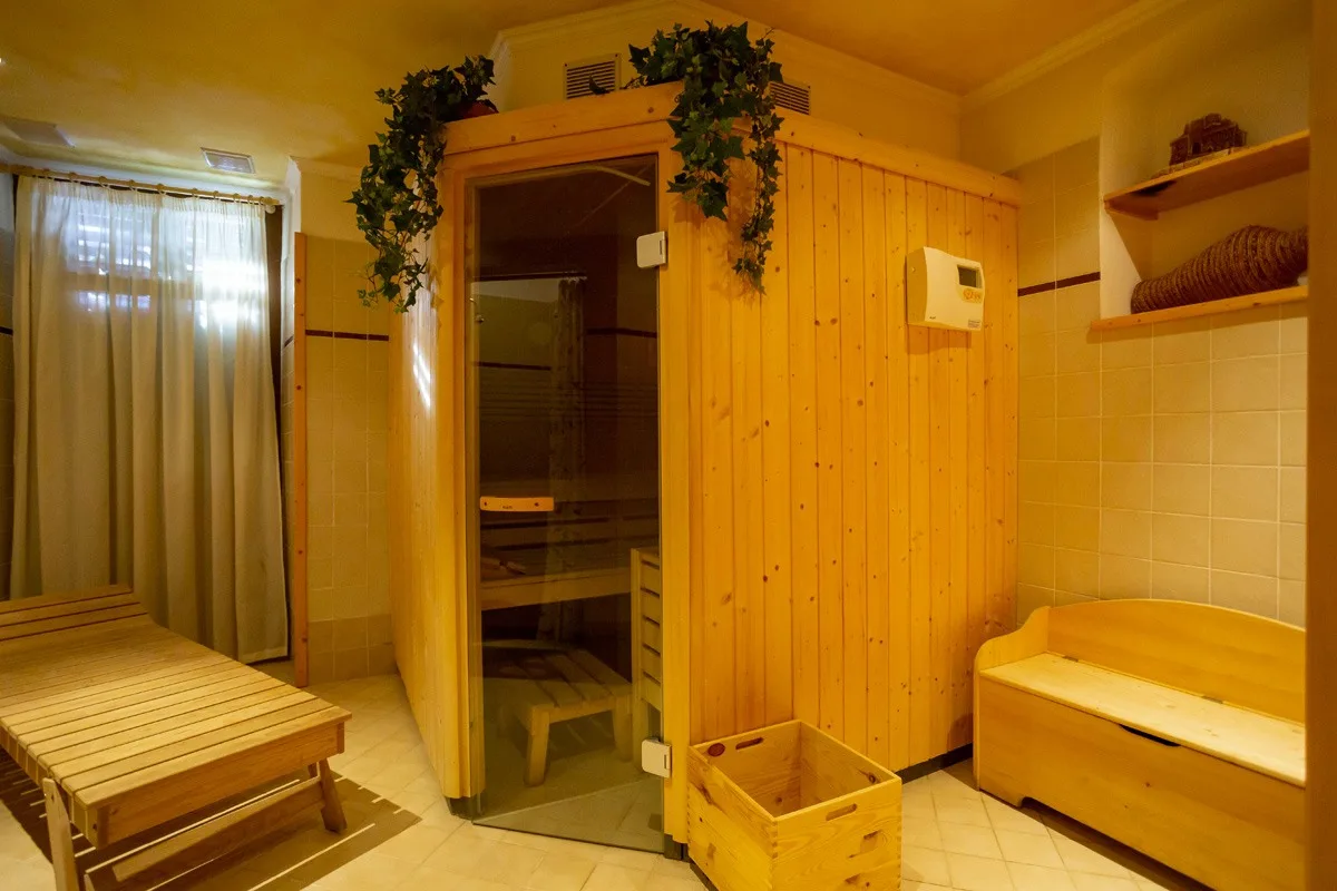 Sauna finlandese in legno con cabina a vetri e panche nella zona benessere