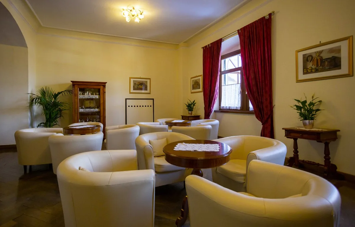 Elegante salotto dell'hotel con poltrone bianche, tavolini e tende rosse