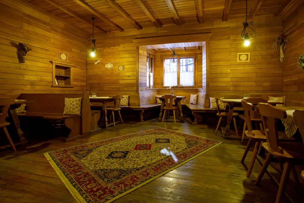 Sala da pranzo rustica in legno con panche, tappeto persiano e illuminazione soffusa