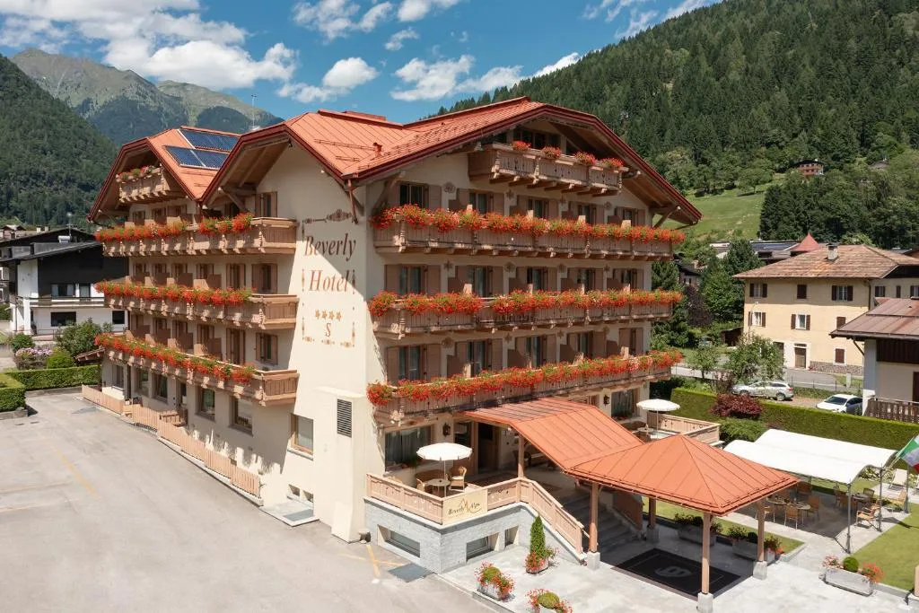 Facciata estiva dell'hotel con balconi fioriti e piazzale antistante