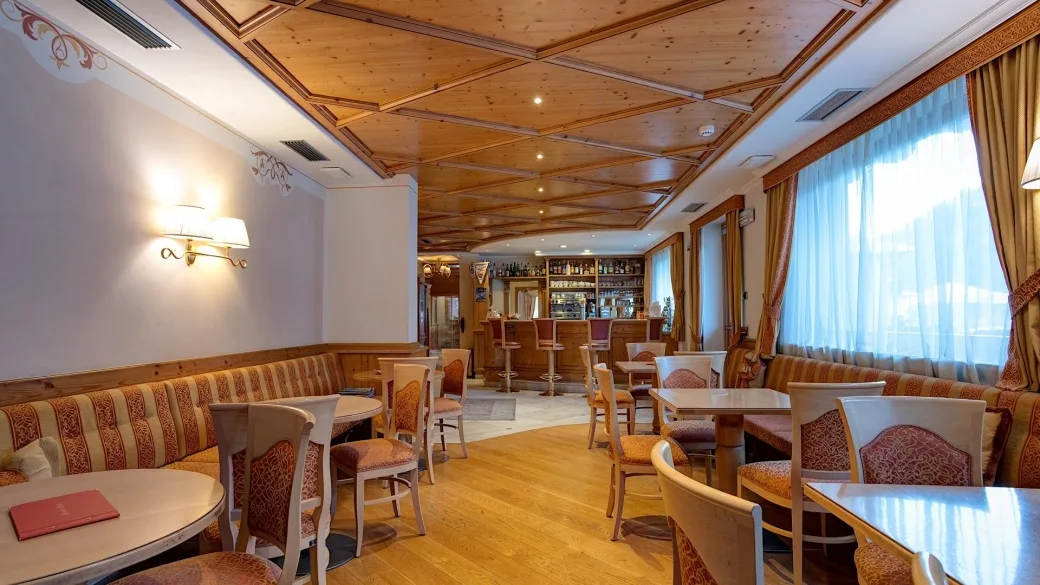 Sala lounge con bar, divanetti e soffitto in legno