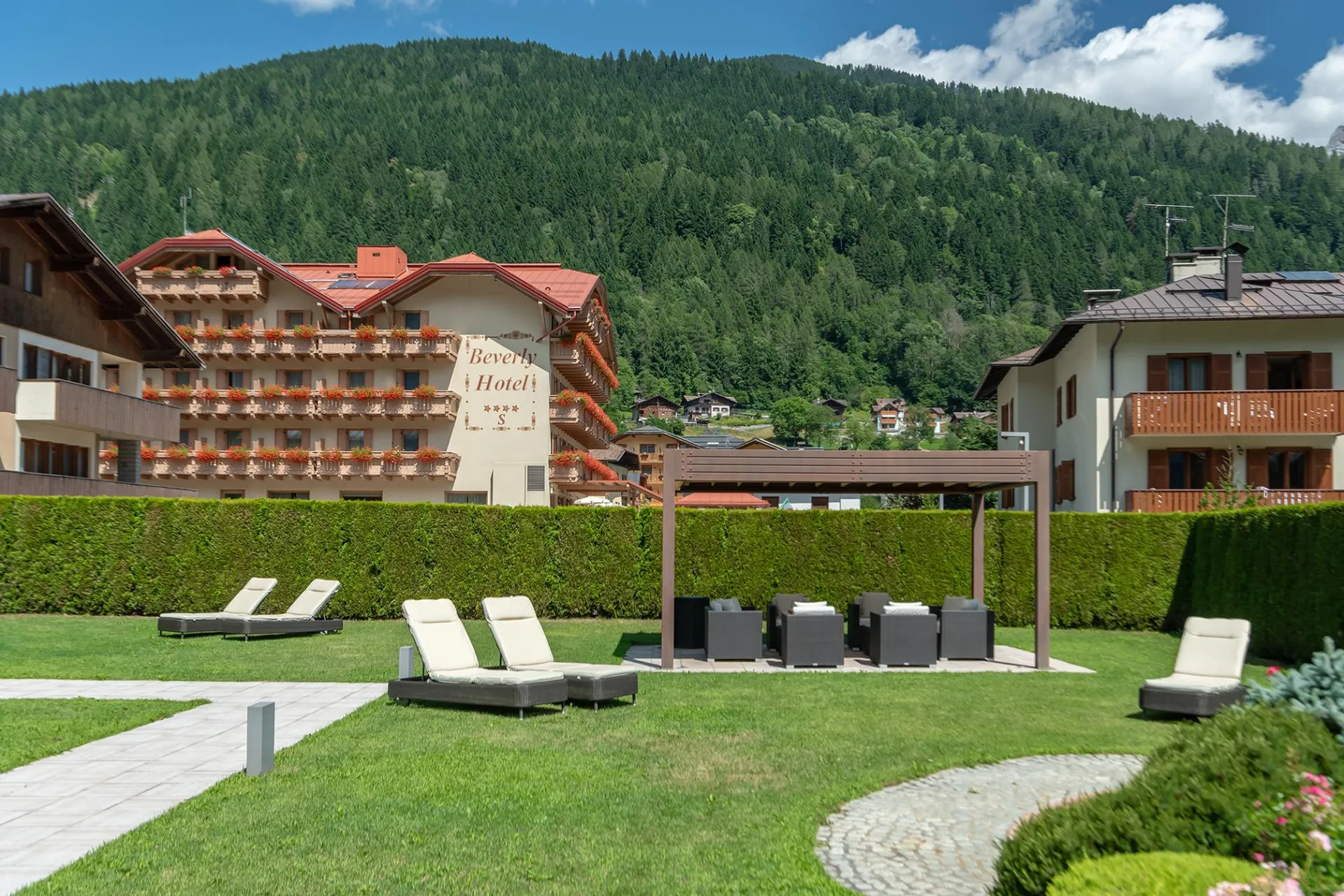Giardino dell'hotel con lettini prendisole e pergolato in estate