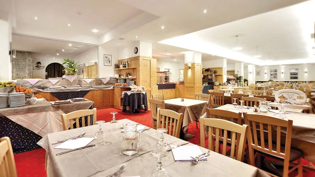 Sala da pranzo dell'hotel con tavoli apparecchiati, buffet e moquette rossa