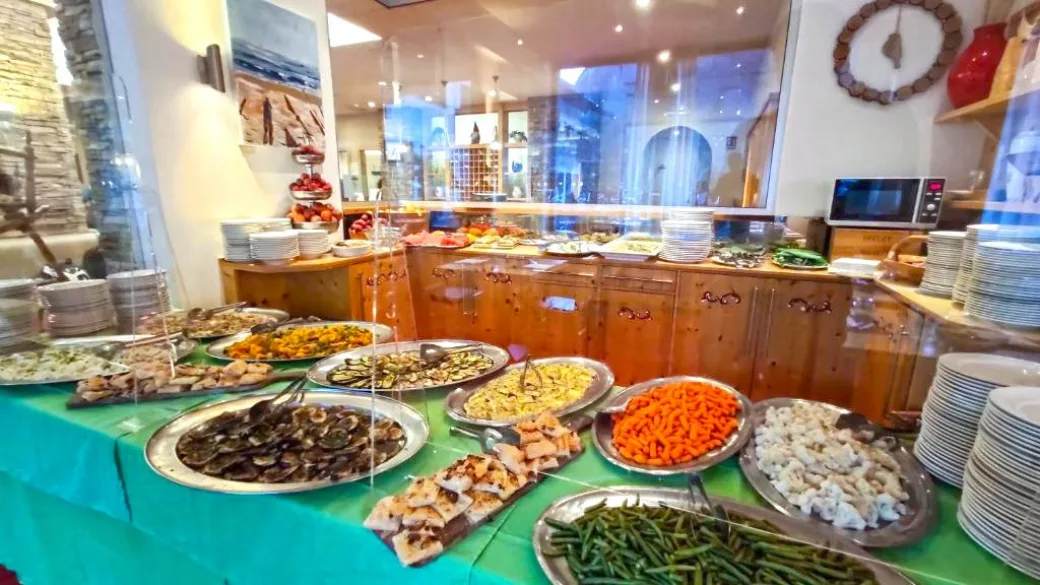 Buffet ricco di piatti con verdure, carote e contorni vari su tavolo con tovaglia verde