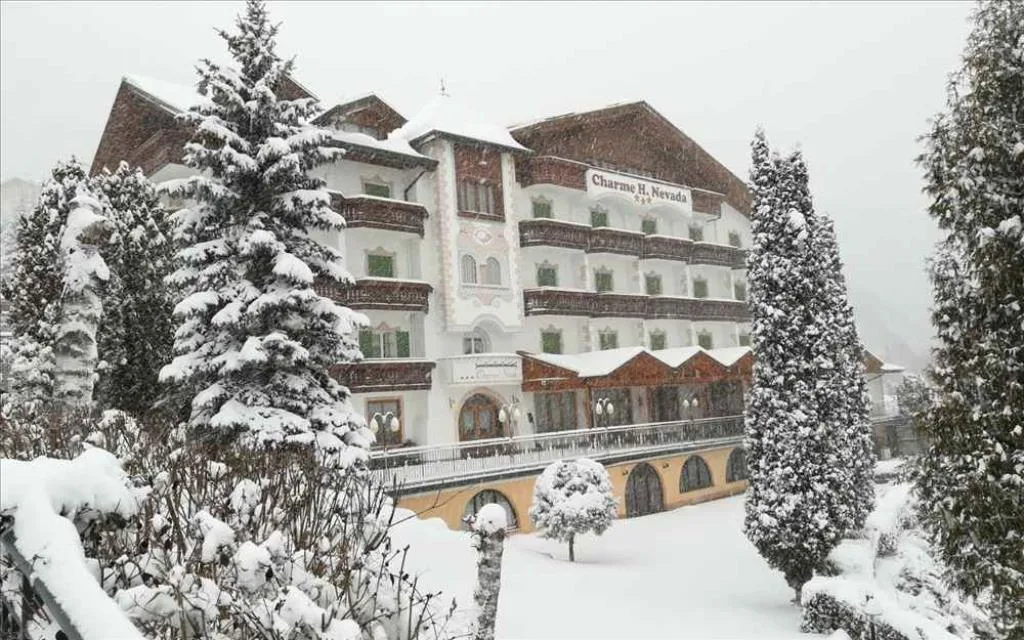 Vista invernale dell'hotel con giardino e alberi coperti di neve durante una nevicata