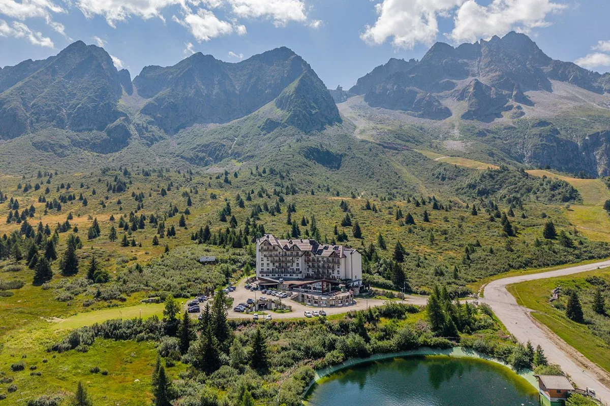 Panorama aereo dell'hotel immerso nel verde con laghetto e cime alpine