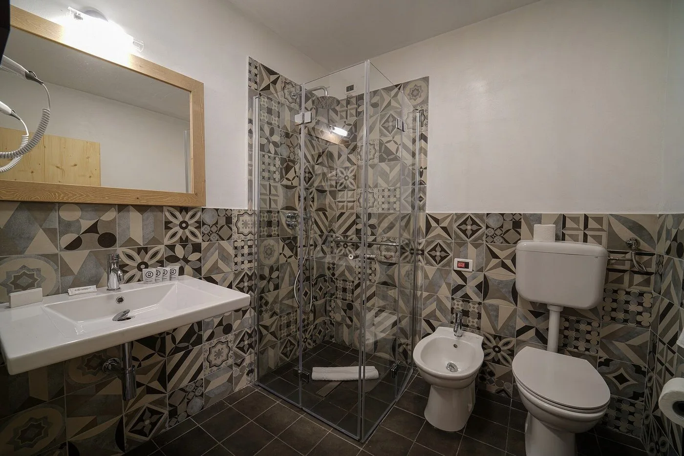 Bagno moderno con doccia in vetro, piastrelle decorative e sanitari bianchi