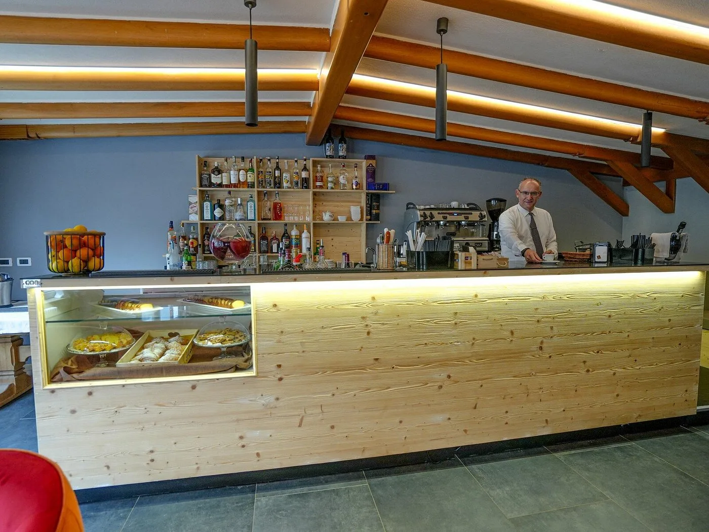 Bancone bar in legno con pasticceria fresca e barista in divisa