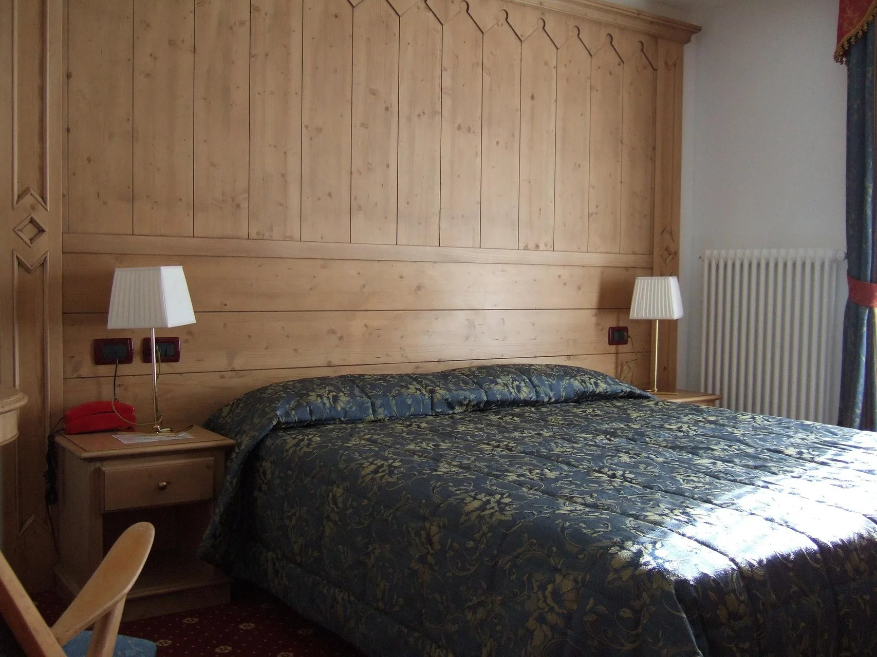 Camera matrimoniale in stile classico con testiera in legno e copriletto decorato