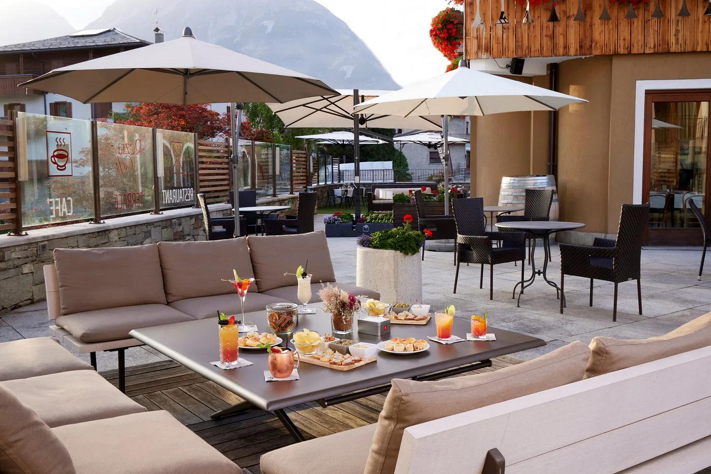Terrazza lounge con divani, tavolo apparecchito con cocktail e aperitivi