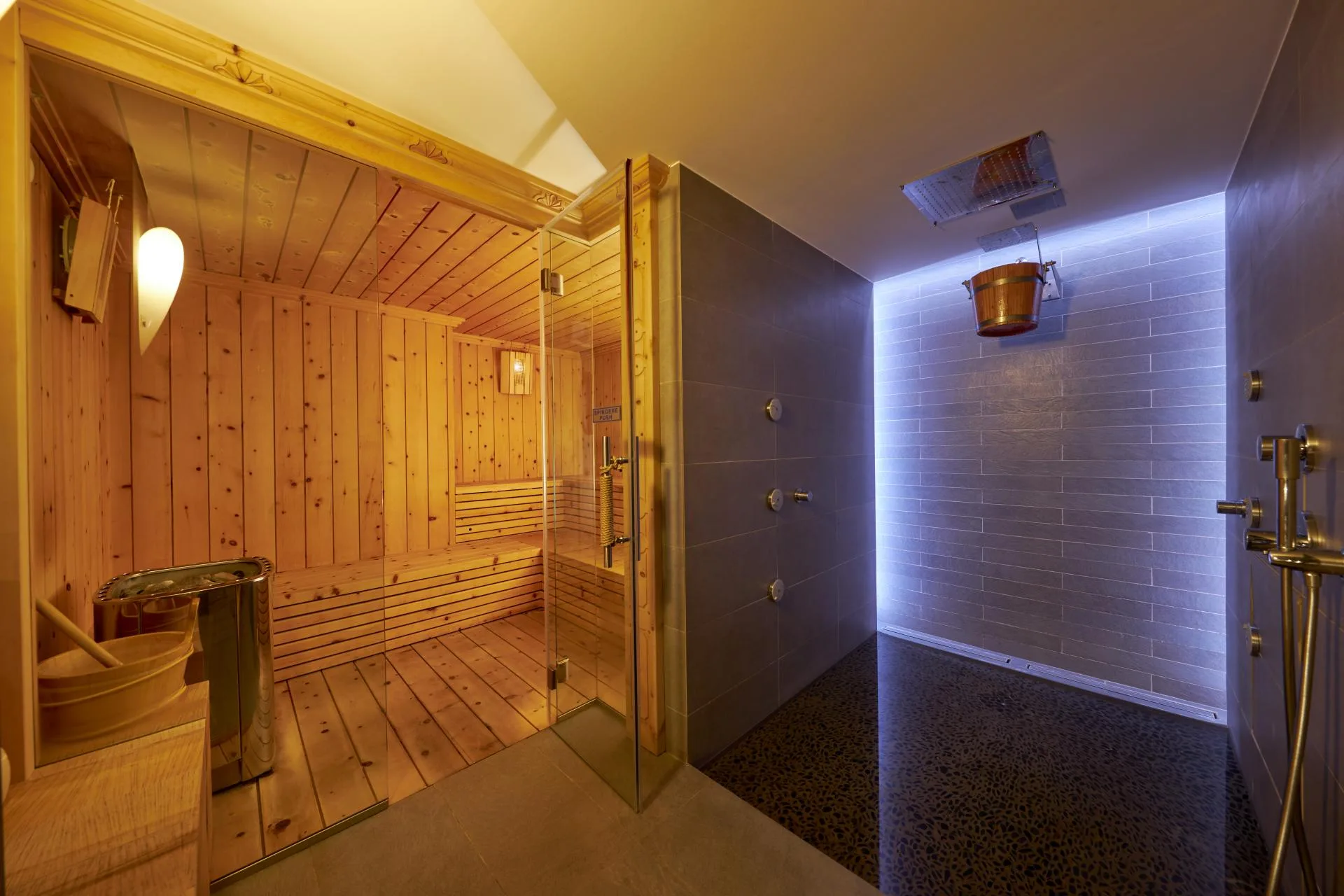 Zona wellness con sauna in legno e doccia emozionale illuminata