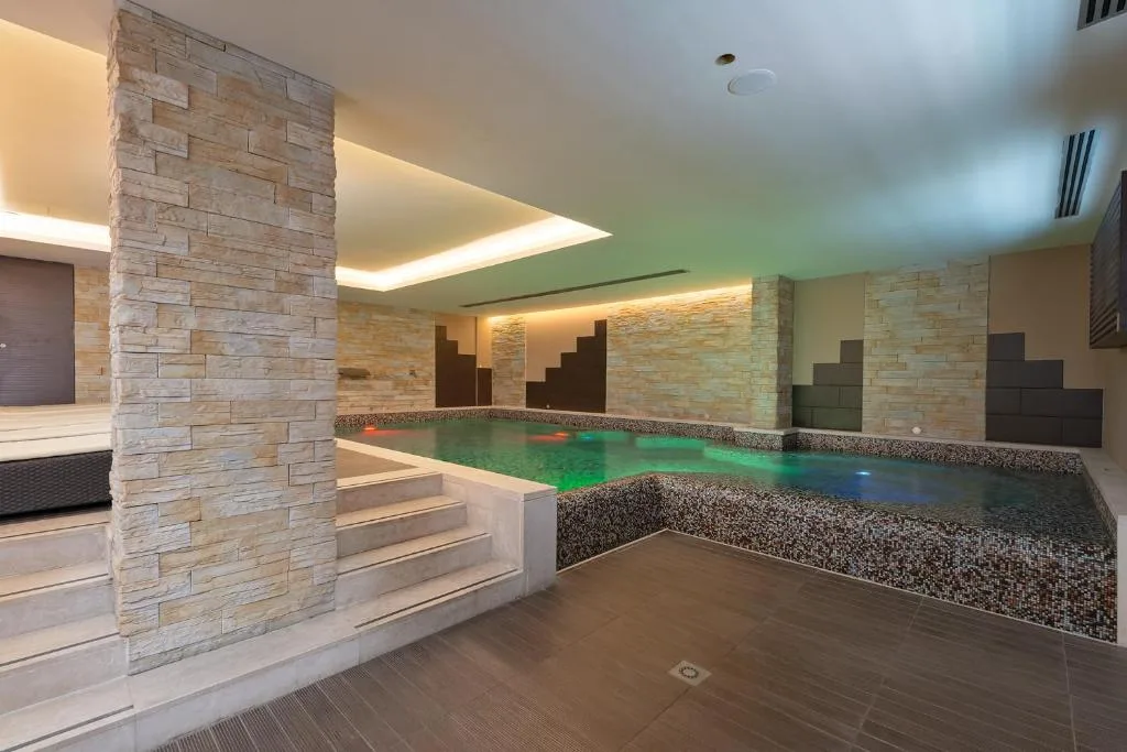 Piscina interna coperta con illuminazione colorata e pareti in pietra decorativa