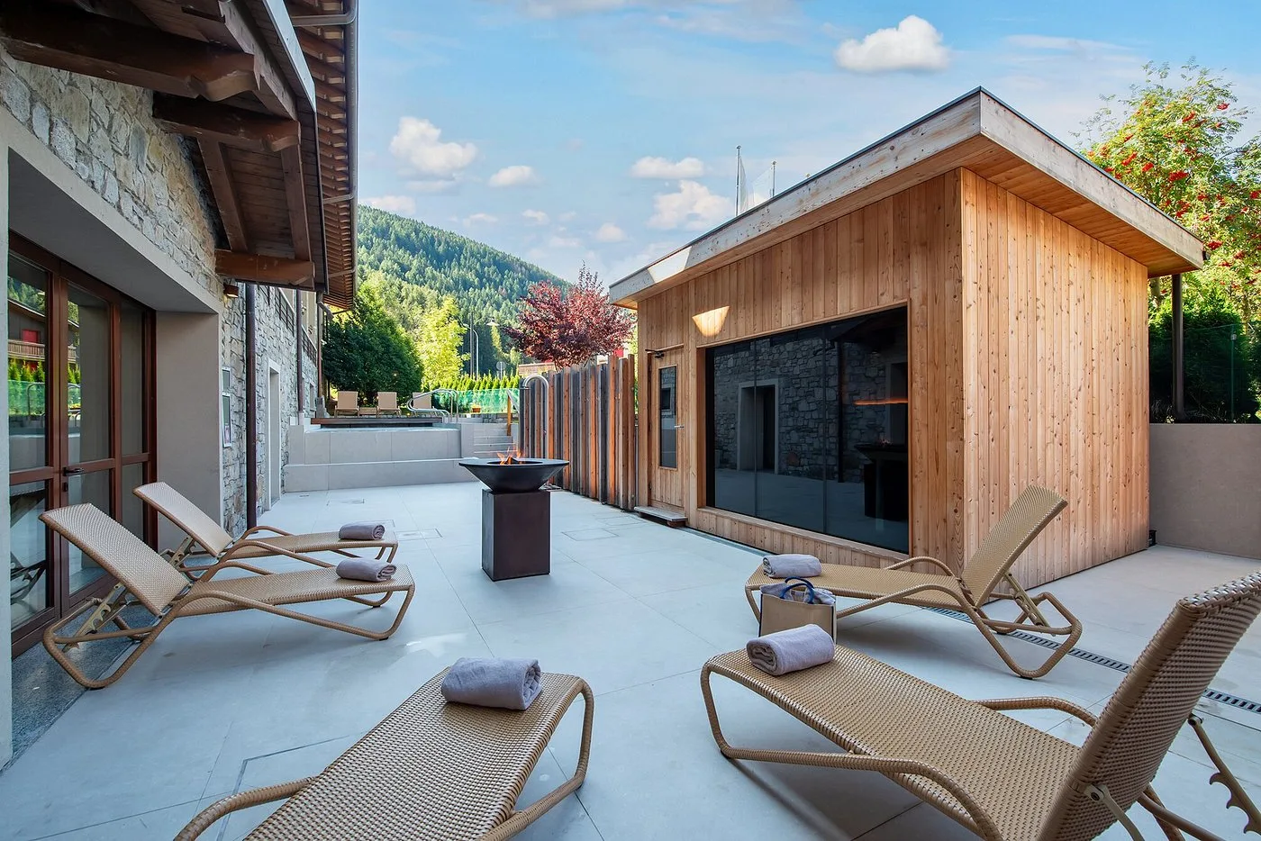 Terrazza benessere esterna con lettini, sauna in legno e vista sulle montagne