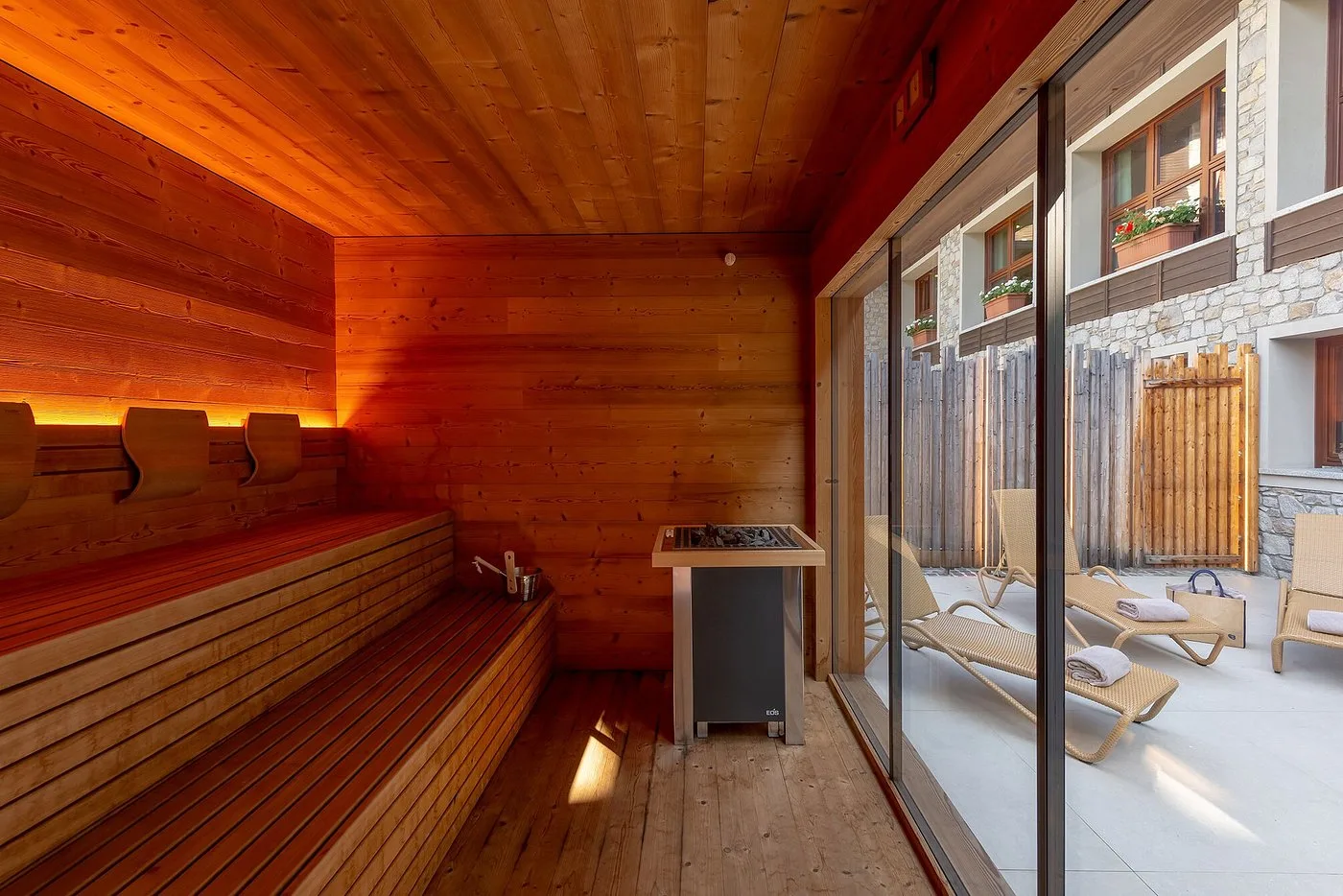 Interno della sauna in legno con vista sulla terrazza esterna attraverso ampie vetrate