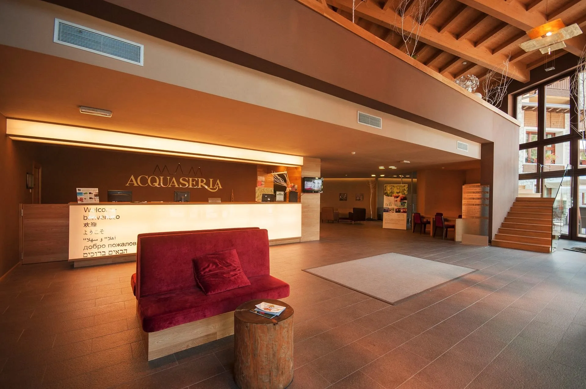 Hall dell'hotel con reception, divano rosso e soffitto in travi di legno