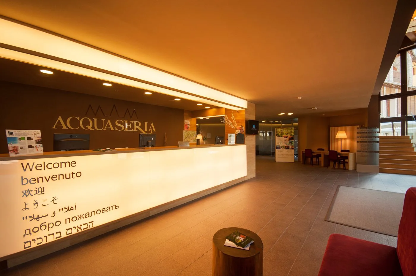 Reception dell'hotel Acquaseria con bancone illuminato e messaggi di benvenuto multilingue
