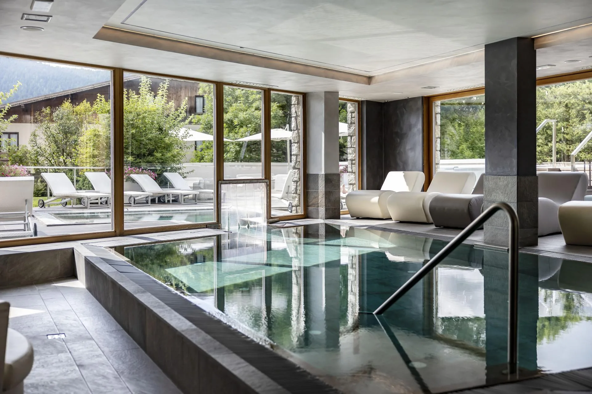 Piscina coperta della spa con lettini relax e vetrate affacciate sul giardino